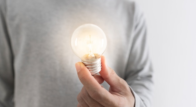 New ideas, innovation and inspiration concept. a man holding glowing light bulb on hand