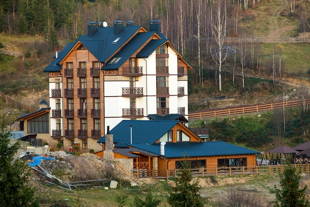 New modern comfortable four-story hotel building with attached premises, attic rooms and high chimneys in ecological rural area on spruce trees spring or summer.