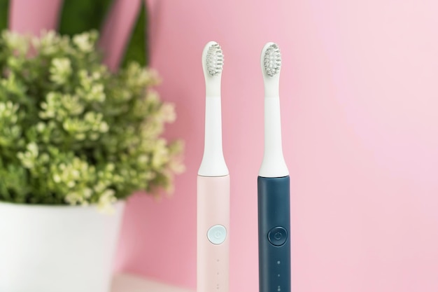 New modern ultrasonic toothbrushes. Dental care supplies with green leaves on pink pastel background. Oral hygiene, gum health, healthy teeth. Dental products Ultrasonic vibration toothbrush.