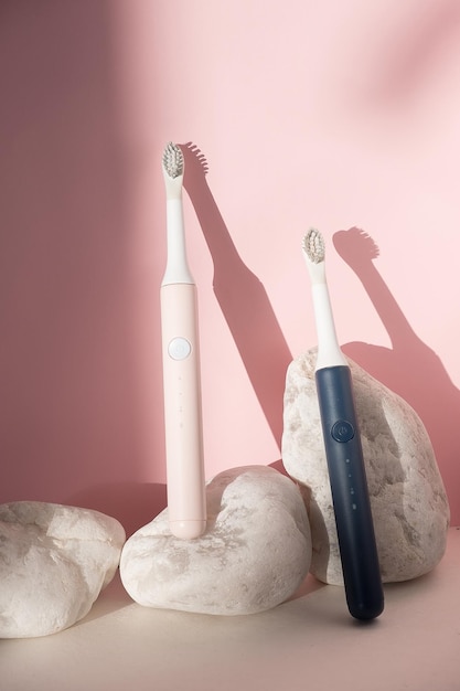 New modern ultrasonic toothbrushes. Dental care supplies with white stones on pink pastel background. Oral hygiene, dental health, healthy teeth. Dental products Ultrasonic vibration toothbrush.