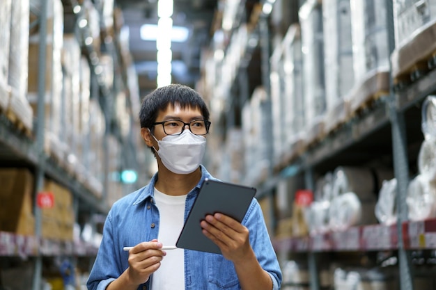 New Normal Asian men, staff, product wearing face mask. counting Warehouse Control Manager Standing, counting and inspecting products in the warehouse