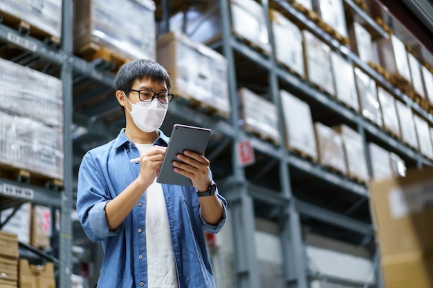 New Normal Asian men, staff, product wearing face mask. counting Warehouse Control Manager Standing, counting and inspecting products in the warehouse