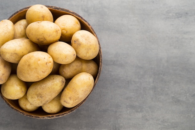 New potato on the bowl, grey table.