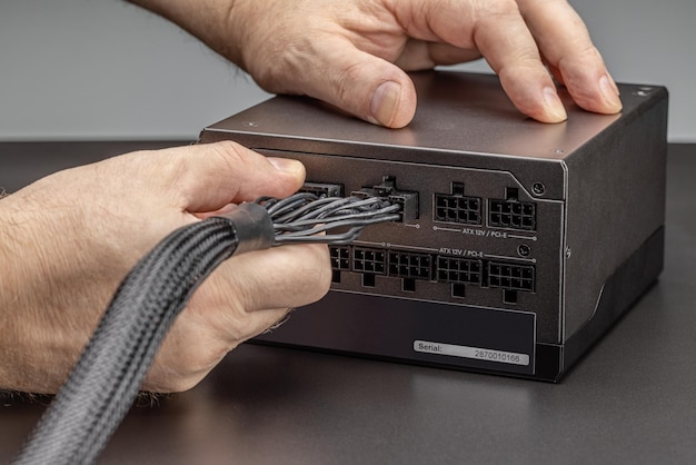 A new power supply for a desktop computer with a set of wires and cables. Connection, men's hands.