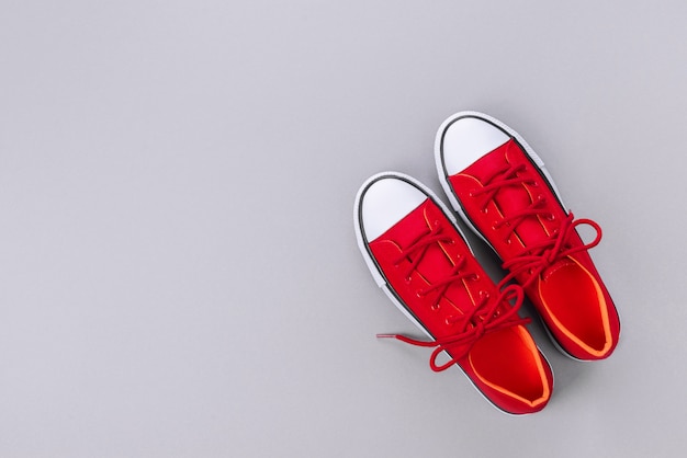 New red sneakers on grey background with copy space.