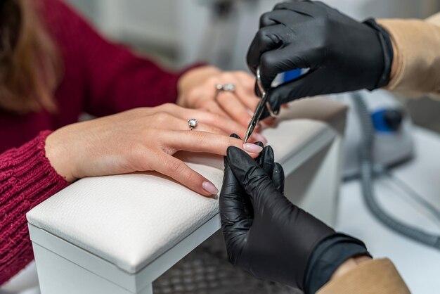 in the new salon, a nail specialist makes a gel varnish coating for a regular client during a pandemic. Manicure concept. Gel varnish coating concept