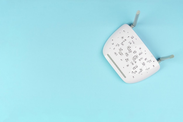 New white WiFi router with gray antennas on a light blue background top view from a copy space