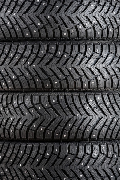 New winter car tires with spikes closeup vertically Texture background