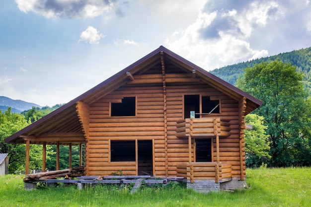 New wooden cottage with balcony, terrace, steep roof under construction