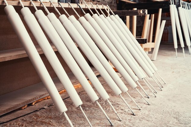 New wooden furniture legs drying after applying paint leaned on large rack in light woodwork shop