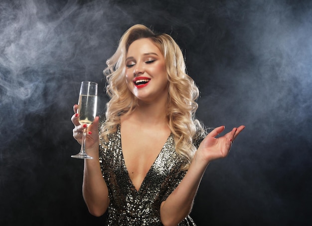 New Year Birthday holiday concept Young attractive woman in evening dress holding glass of champagne