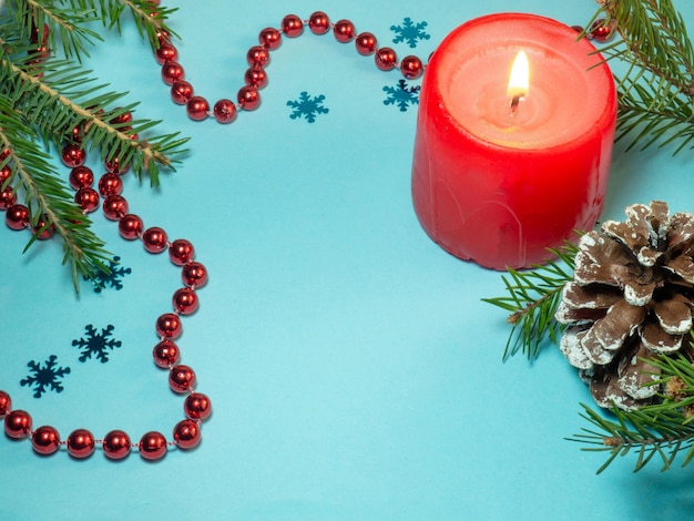 New Year card Christmas card on blue background Fir branches Decorations for the holiday Red beads candle and fir cones