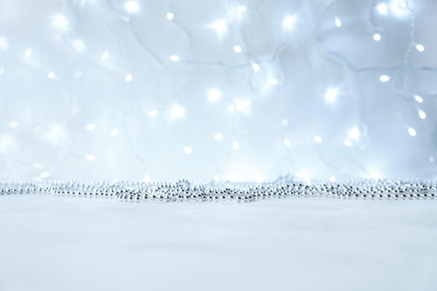 Photo new year and christmas background with silver garlands with lights with bokeh in blur. gray neutral colors with copy space and mock up.