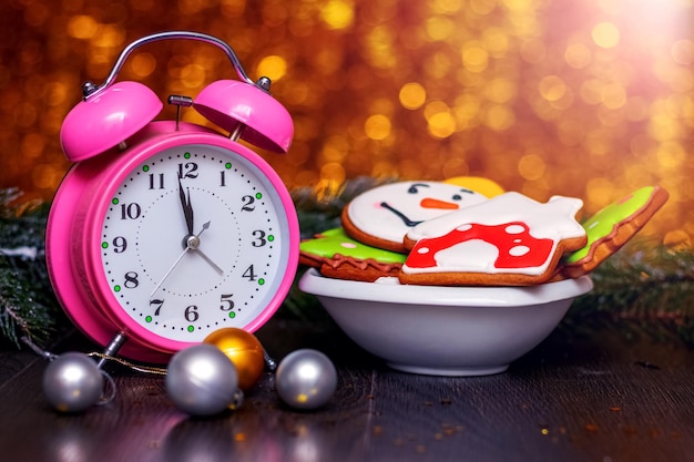 New Year and Christmas cookies in a plate near an alarm clock and a fir tree branch