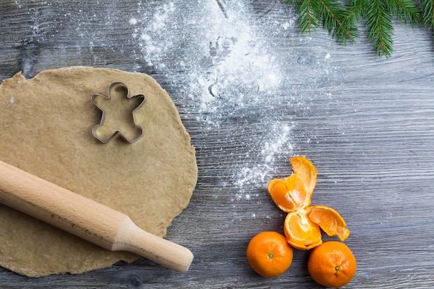 New Year and Christmas decorations on a wooden surface with tangerines and a Christmas tree Prepare and roll out the dough for baking gingerbread