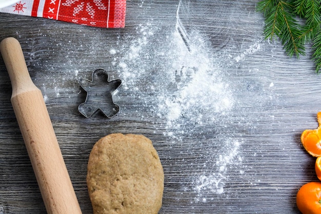 New Year and Christmas decorations on a wooden surface with tangerines and a Christmas tree Prepare and roll out the dough for baking gingerbread