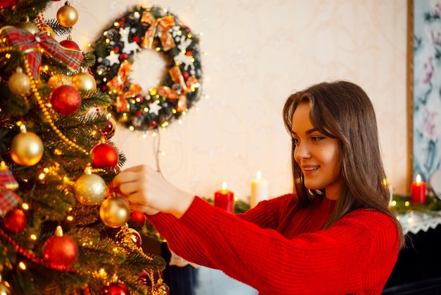 New Year and Christmas time festive winter season preparation for holidays Beautiful smiling girl decorating Christmas tree