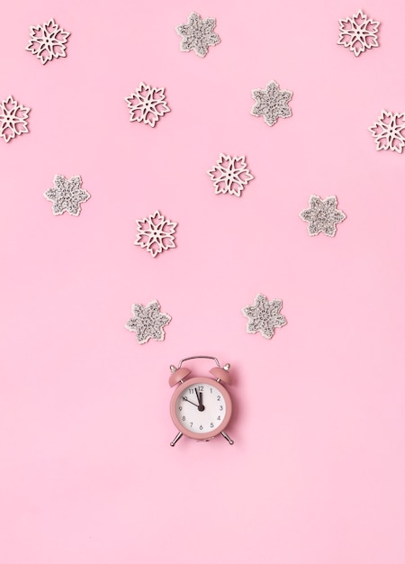 New Year Christmas top view flat lay pink alarm clock with snowflakes copy space background.