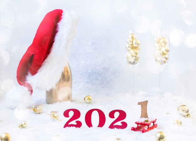 New year Composition  with Champagne bottle, 2021 numbers and santa hat on snowy floor