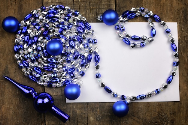 New Year composition with garlands and balloons on a wooden table and a blank sheet of paper