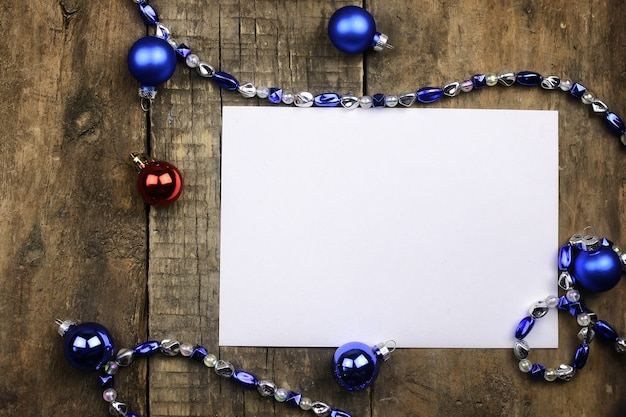 New Year composition with garlands and balloons on a wooden table and a blank sheet of paper