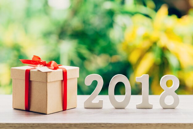 New Year concept for 2018 : Wood numbers 2018 on wood table top and gift box with green light bokeh blur background.