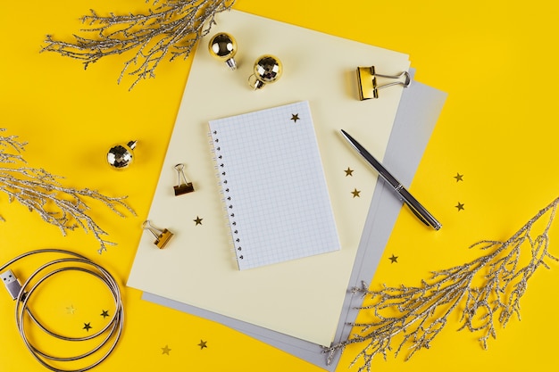 New year decoration of yellow office desk table with blank notebook and other office supplies. Top view with copy space, flat lay.