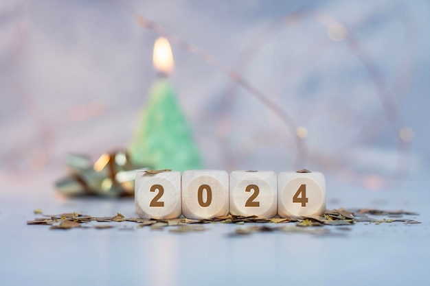 New Year holiday background Inscription on wooden cubes of the number 2024 with bright glowing lights