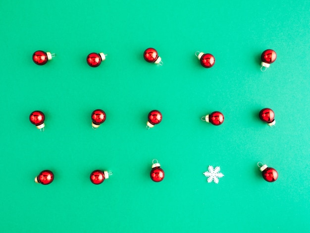 New year pattern, layout, flat lay. A lot of red Christmas tree toys lie on a green background.