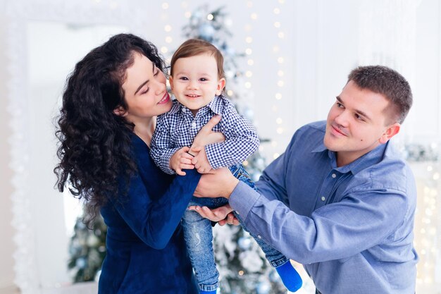 New Year photo session in the studio happy parents with little boy on Christmas tree background