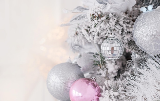 New year pink, silver and turquoise Christmas decorations with balls and bows on the background of Christmas lights. Light background. White, gray. Background for postcards