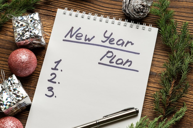 New year plan inscription in notebook with spruce branches and Christmas tree toys