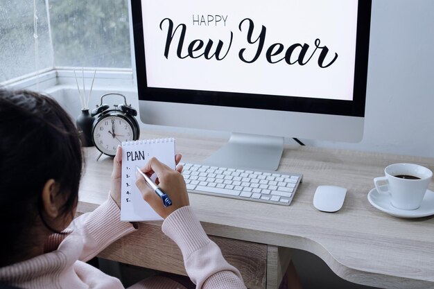 New year plan and resolution. Woman in pink sweater writing plan list in open notepad. Start new yea