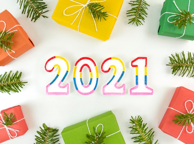 New Year postcard with fir tree branches, gift boxes, and 2021 figures on white background.