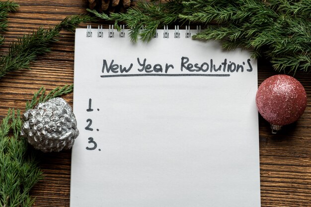 New year resolutions inscription in notebook with fir, spruce branches and Christmas tree toys