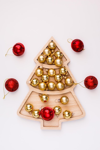 New Year's Eve white Christmas tree-shaped plate on a wooden tray with gold balls and dice with the number 25. New Year's concept with room for text