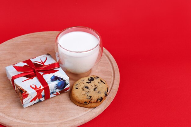 New Year's gift, a glass of milk and cookies with chocolate chips on a red background. free space for text