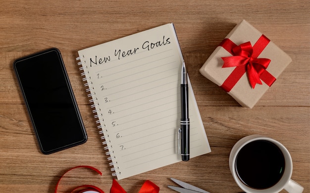 New Year's Goals List written on Notebook with gift box and smart phone