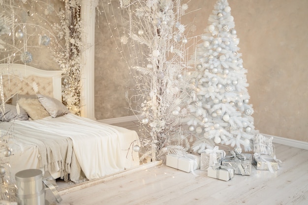 New Year's holiday, mood, Stylish New Year's minimalistic interior, Gifts and wrapped gifts under the Christmas tree. large white bedroom with white bed