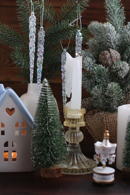 A New Year's house with a burning candle inside Christmas decorations on a wooden tray with burning candles