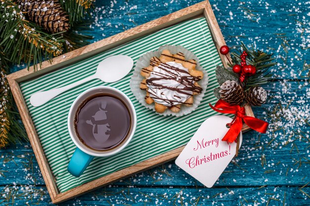 New Year's photo of tea with snowman, cake on table with spruce branches, postcards with Christmas wish