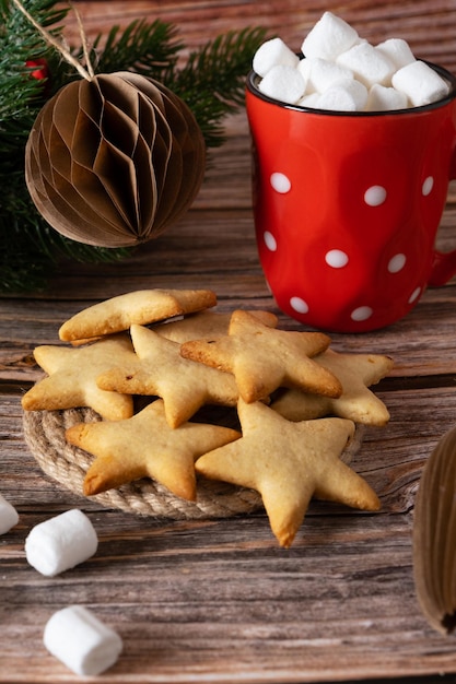 New Year's starshaped cookies made at home next to a red mug of marshmallow