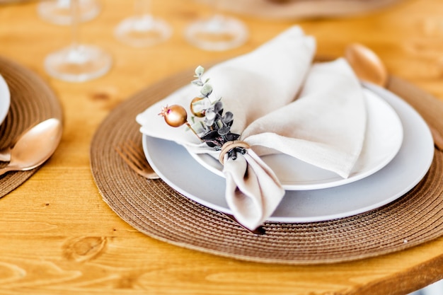 New Year table decor. A white napkin with decor lies on the plate, under the plate there is a bronze-colored countertop.Photo