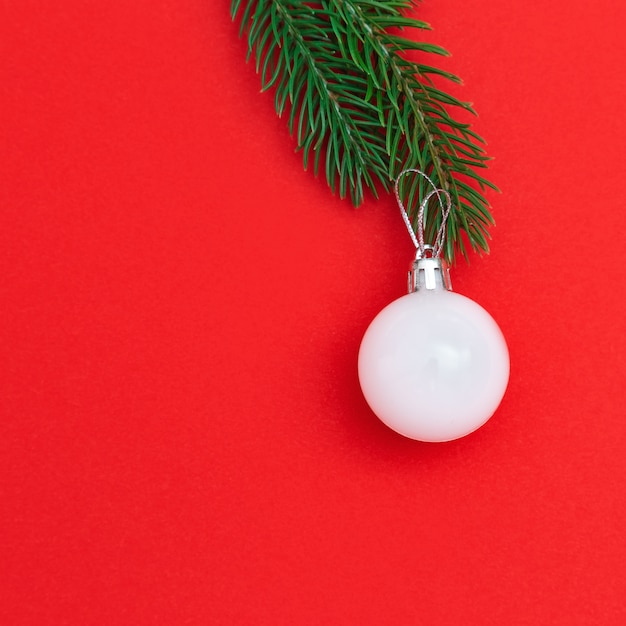 New Year white holiday ball on green fir tree twigs. Creative minimal celebration concept for xmas. Flat lay. Top View. 