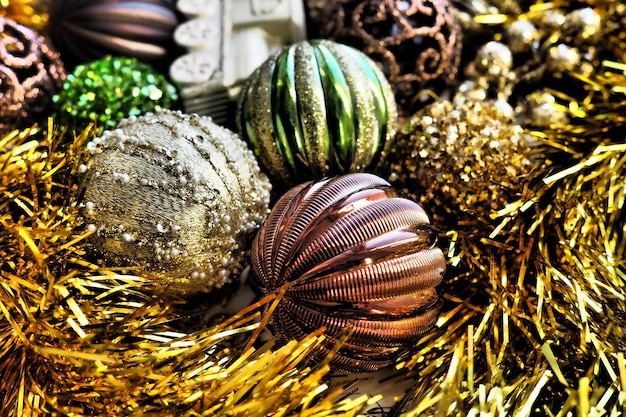 New Years Christmas balls tinsel and decorations close up A lot of decoration of golden brown yellow green Striped Christmas balls Festive beautiful colorful background Home holidays design