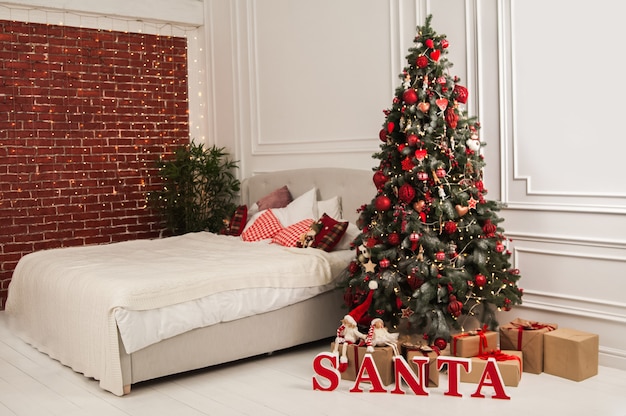 New Years decor of the bedroom in the Scandinavian style Christmas tree Santa Claus and bed with pillows Hygge New Years concept Selective focus