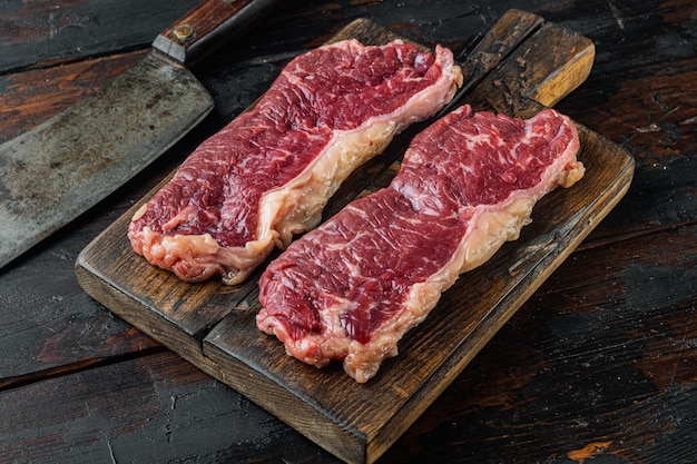 New york beef steaks, on old dark  wooden table background