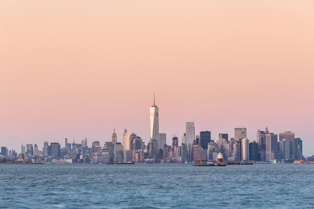 New York City Manhattan downtown skyline at dusk with skyscrapers illuminated over Hudson River panorama. Vertical composition, copy space.