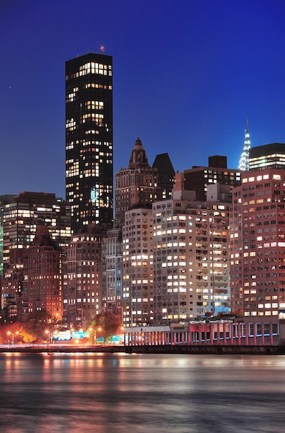 New York City Manhattan midtown skyline at night over East River.