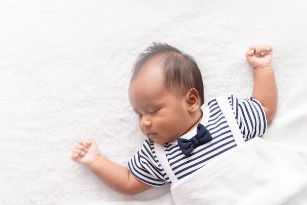 Newborn asian boy baby sleeping on white furry